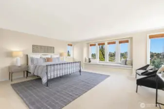 Upstairs you'll find the expansive primary suite - plenty of space to sit up here! Window bench plus a full seating area and walls of windows.