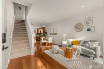This bright, open-concept main living area features a sleek staircase with light wood treads, newly painted interior, seamless flow into the kitchen and dining nook.