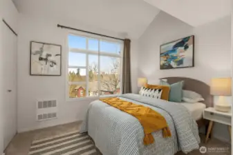 This cozy guest bedroom features a high ceiling, large windows with forest views.