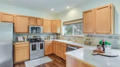 Kitchen offers all SS appliances, stunning hardwoods, and ample counter & cabinet space with views to the back yard.