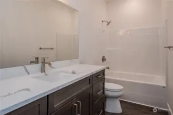 The Full Bathroom in the upstairs hallway boasts excellent storage space, quartz counters, a full bath/shower combo and luxury vinyl plank (LVP) flooring, blending modern style, durability and function.