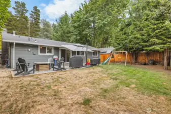 Exterior backyard with patio and firepit area, partial shade, ready for entertaining