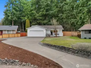 Inviting front exterior with wide driveway, 2 car garage and RV parking, covered front porch, and a level, landscaped yard