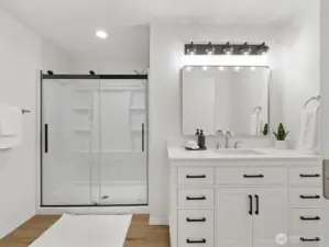 Completely remodeled primary bathroom with modern vanity and fixtures, large shower and continued LVP flooring