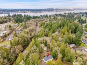 Directly above Port Orchard. Natural summer breezes (convection) rise up hill off the water, helps with cooling on the hottest days of summer. Privacy-security buffers on 3 sides: North to Sinclair Inlet, East (right side), and West (left side).