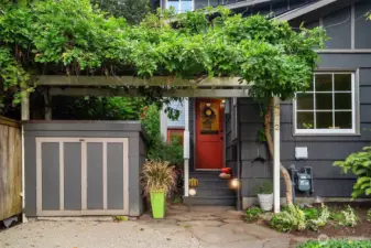 The wysteria blooms across the arbor. And a garbage and recycle garage on the left.