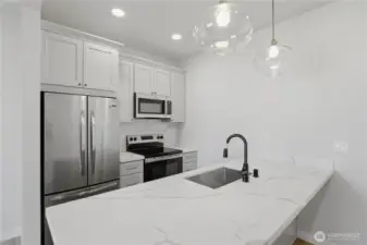 Modern kitchen with quartz countertops, stainless appliances, and island seating