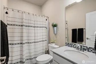 Main floor full bathroom w/quartz counter top & tile backsplash.
