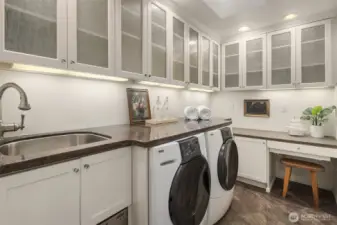 Thoughtful laundry room with abundant cabinetry, counter space, and storage