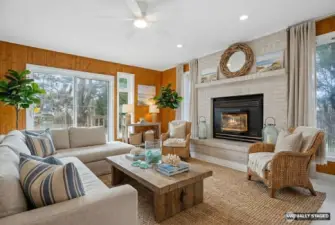 Virtually Stage living room with cozy gas fireplace and entry point to the exterior deck space and fully fenced yard.