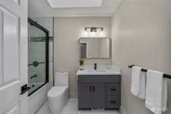 The updated second bathroom features sleek, modern hardware that adds a touch of elegance to the space. The contemporary fixtures and fittings enhance the overall aesthetic, creating a stylish and sophisticated atmosphere. With its clean lines and minimalist design, this bathroom offers a refreshing for relaxation.