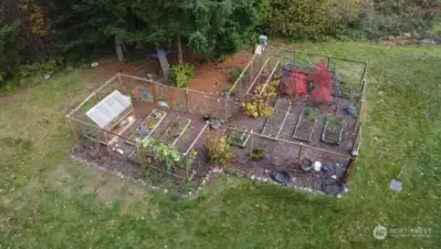 Fenced garden with greenhouse, raised beds and irrigation system.