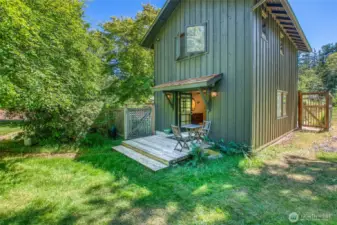 Charming deck off the main-level primary bedroom, with french doors opening to views of the natural grounds and nearby pond.