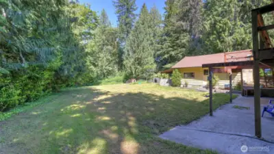 This expansive open area, wrapped in mature trees and lush greenery, offers an ideal setting for recreation, play, and enjoying the outdoors