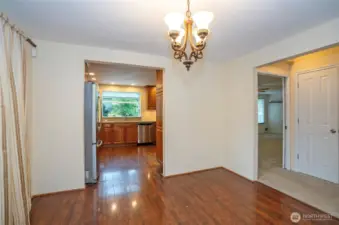 Dining area with a view down the hallway to the family room and kitchen, featuring beautiful flooring that flows seamlessly through both spaces.