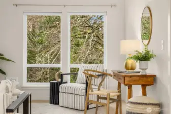 Corner seating vignette framed by oversized windows, creating a bright and inviting space ideal for reading, working, or relaxing.