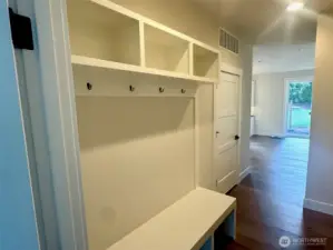 mudroom area just inside from garage with built-in bench, cubbies and coat rack.