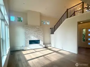 Great room has soaring ceilings and stacksone faced linear gas fireplace and a raised tile hearth.