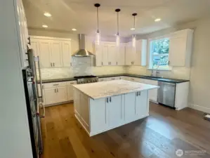 Chef's Kitchen has large island and abundant custom cabinets.   Perimeter counters have a unique leather textured quartz counters.