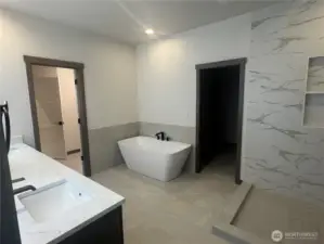 Primary Suite bath.  offers tile floors and direct access to walk in closet and laundry room.