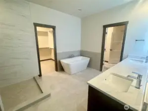 Primary Suite bath.  offers tile floors and direct access to walk in closet and laundry room.