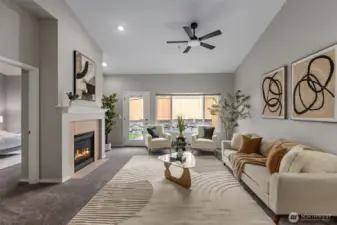 Bright living room with gas fireplace, ceiling fan and vaulted ceilings.
