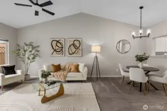 Bright living room with gas fireplace, ceiling fan and vaulted ceilings.