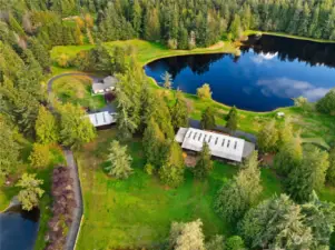 Overview of the part of the acreage showing both shops, the lake and the house.