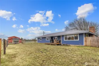 Rear exterior of home, showing the expanded deck & fenced front yard.