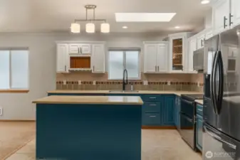 View of kitchen with Corian counters, newly updated cabinets, newly updated appliances, and lighting. Note the skylight in the kitchen.