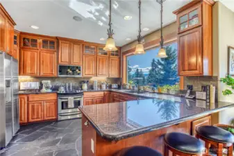 Kitchen has S. African slate flooring, granite countertops, bar seating, stainless top-end appliances, & beautiful wood cabinets. Another incredible lake view from the large picture window behind the double sink.