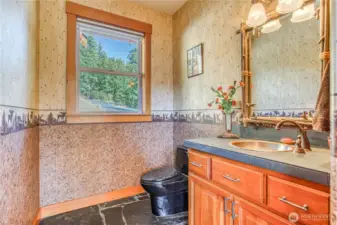 Half bath off the living area has a window to the driveway side, slate flooring, ceramic tile counter, & beautiful copper sink.