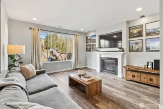 Bright living room with large windows, gas fireplace, and comfortable gathering space.