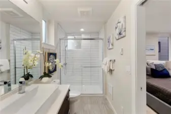Picture of previous model home primary bathroom.  All home feature primary bathrooms with tiled showers and floors, dual sinks, and built in storage alongside modern cabinetry.