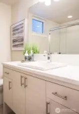Main level bathroom compete with soft-closing Belmont cabinetry, quartz counters and backsplashes, tiled flooring and tiled large showers.