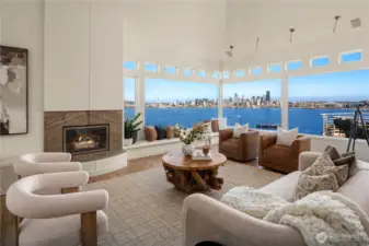 The wood burning fireplace features a gas log lighter and marble surround. The picture windows are flanked with abundant transom windows overhead.
