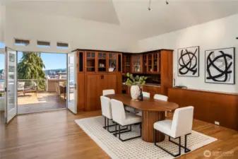 Just off the main living area is a private view deck complete with outdoor kitchen. The dining room is surrounded by custom cabinetry with a separate bar sink and hammered metal backsplash in the foreground.