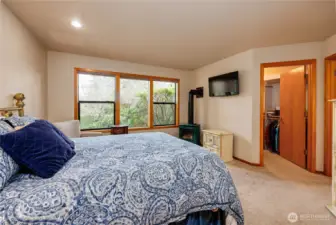 Primary bedroom has wall of windows, a propane fireplace and walk-in closet.