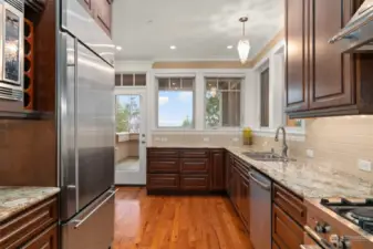 A chef's kitchen with luxurious cabinetry, marble counters and stainless steel appliances.