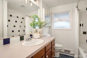 The main floor bathroom (one of two) features tiled floors and tub surround as well as fantastic storage.