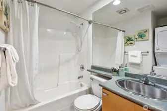 Bath is clean and modern, including tub surround and washer/dryer unit.