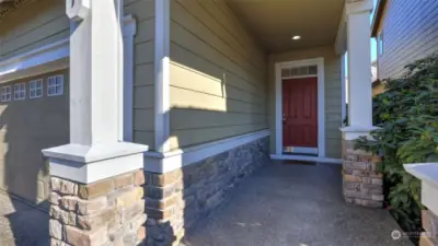 Cozy covered front porch with charming brick detailing.