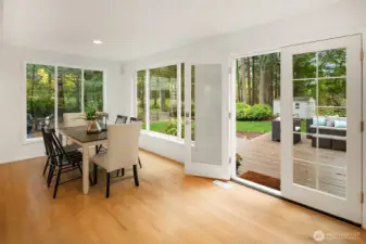 The expansive casual dining area features oversized windows that flood the space with natural light and a seamless transition to the outdoor deck—ideal for effortless indoor-outdoor entertaining.