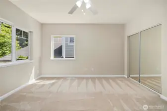 Bright upstairs bedroom with ceiling fan and mirrored closet doors