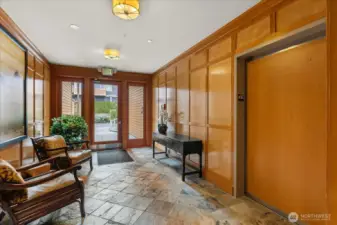 Wood paneled lobby with slate tile flooring to access elevator . . .