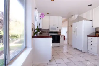 Open Kitchen with Custom design Granite counter tops, White on white millwork, and a Newer Refrigerator and Dishwasher.