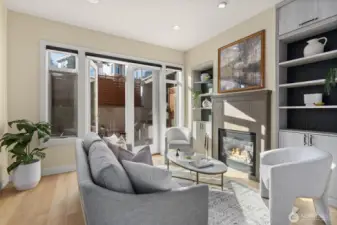 Living room is drenched with sunlight, boasting high ceilings, built in bookshelves, topped off with a cozy gas fireplace.
