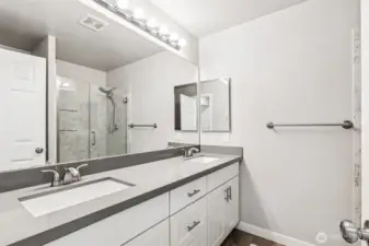 The light and bright primary en-suite bathroom with a dual sink quartz vanity.