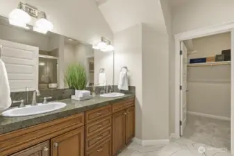 The primary bathroom features a double vanity with plenty of cabinet storage, an oversized shower, and brand new tile flooring. It leads to a large, walk-in closet.