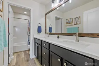 Upstairs Full bath is centrally located adjacent to the rec room and has been updated in 2022 with new LVP flooring, Quartz Countertop, undermount sink and faucet, vanity hardware, new lighting and mirror.